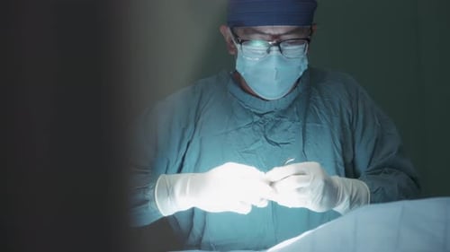 A male surgeon working with scissors during a surgical procedure