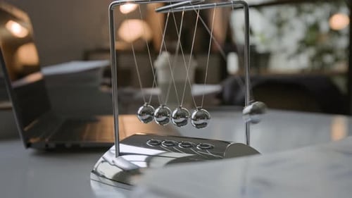 Close up of Silver Newtons Cradle Next to Laptop