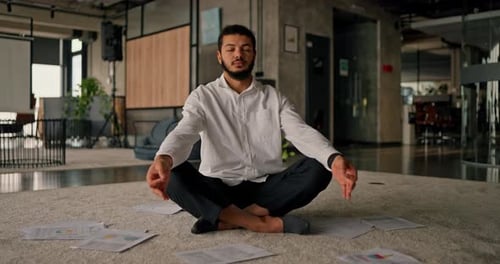 A Side View of an African American Office Worker Sitting in the Lotus Position Meditating on a