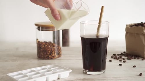 Iced coffee with vegetable milk in a large glass. Making summer iced coffee for breakfast