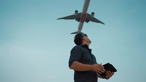 Young Man Following Airplane flying over the sky