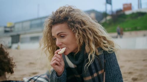 Woman Eating on Beach on Cloudy Day