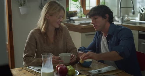 Young Couple Eating Breakfast and Chatting in Kitchen