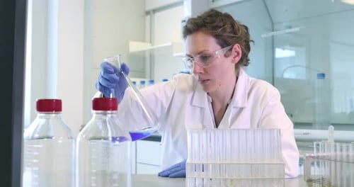 Woman Scientist Mixing Chemicals in Beaker at Lab