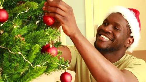 Man Decorating Christmas Tree in Santa Hat