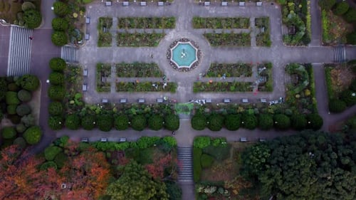 A formal garden with symmetrical design and central fountain during dusk, aerial view