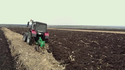Red tractor plowing the field in Ukraine