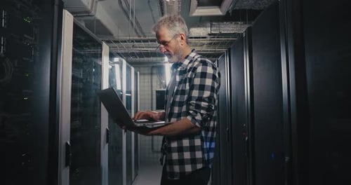Man Using Laptop in Server Room