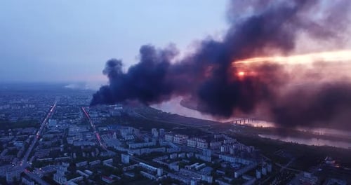 Black smoke rising over cityscape, drone view.