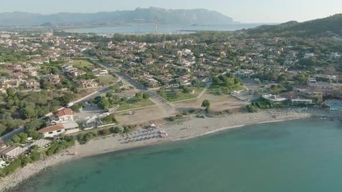 Drone footage of sardinia coastline seascape during summer holidays season, umbrella sand beach trav