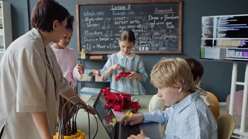 Female Teacher Helping Schoolboy with Coding in Robotics Class