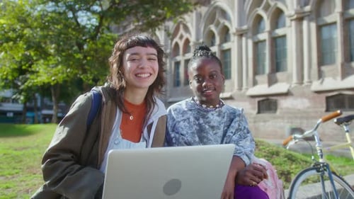 Portrait of Two Cheerful Girls with Laptop on College Campus