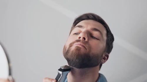 Man Trimming Beard with Electric Trimmer Close Up