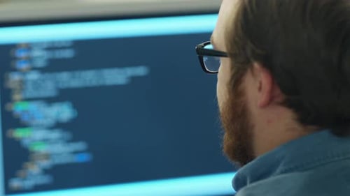 Close-up of a Man's Head in the Background Computer Screen with Code Line is Seen.