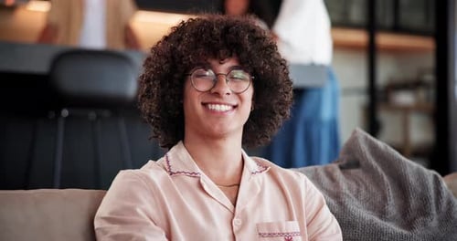Smiling Young Adult with Curly Hair Sits Indoors