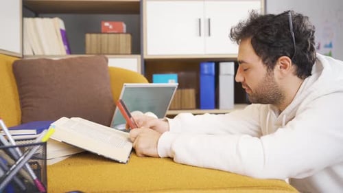 Man Relaxes on Couch Using Phone and Laptop