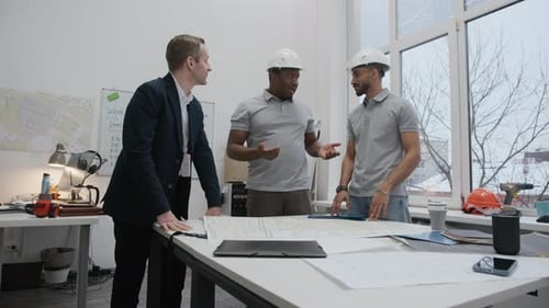 Architects and Engineer Reviewing Blueprints at Workplace
