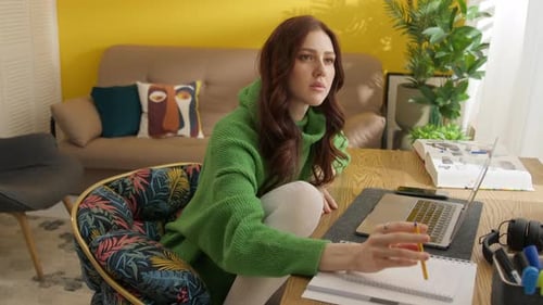 Woman working on laptop, taking notes at desk