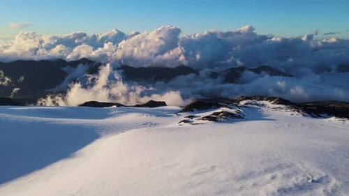 a Snowy Mountain Covered in Clouds with a Blue Sky in the Background