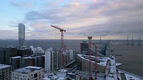 Snow-Dusted Rooftops And Red Construction Cranes