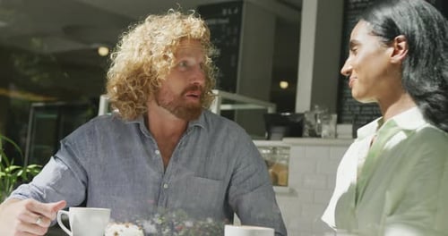 Happy diverse couple drinking coffee and talking in cafe