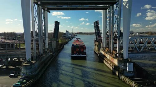 Bulk cargo ship navigating through the draw bridge aerial view.