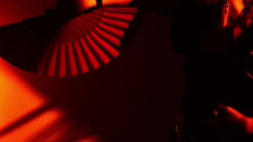 Woman Dancing with Red Fan in Shadows