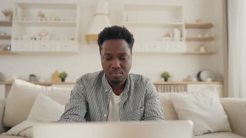 Young Adult Man Works on Laptop at Home