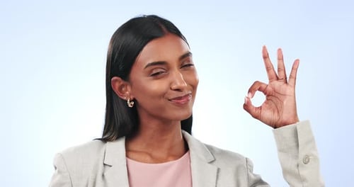 Okay hands, face and business woman in studio for vote, review or feedback on blue background