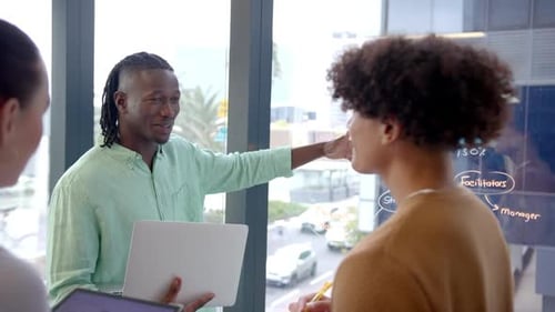 Discutindo o projeto, colegas usando laptop e quadro branco em uma reunião de escritório moderna