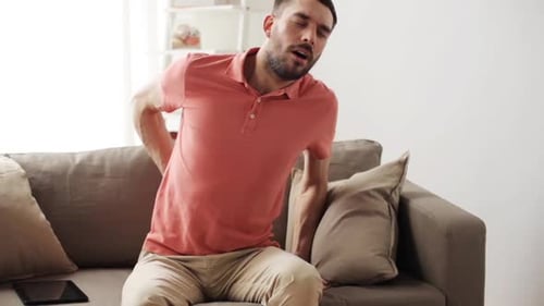 Man Sitting on Couch Massaging Lower Back