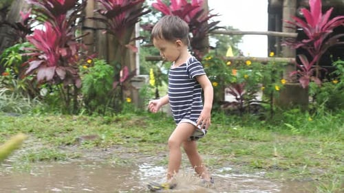 Toddler Splashes Joyfully in Muddy Puddle Outdoors