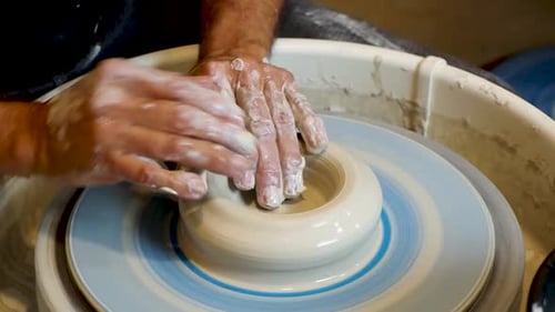 Close up of the potter's hand shaping and molding clay on a turning wheel .