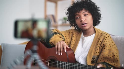 Woman Singing, Playing Guitar and Recording Video