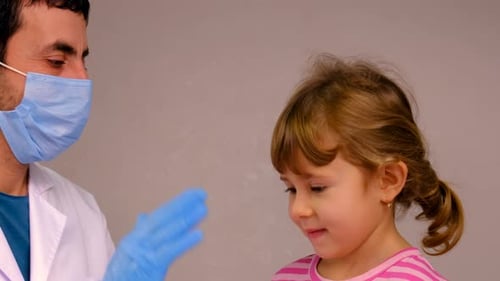 Little Girl High Fives Doctor Wearing Mask and Gloves