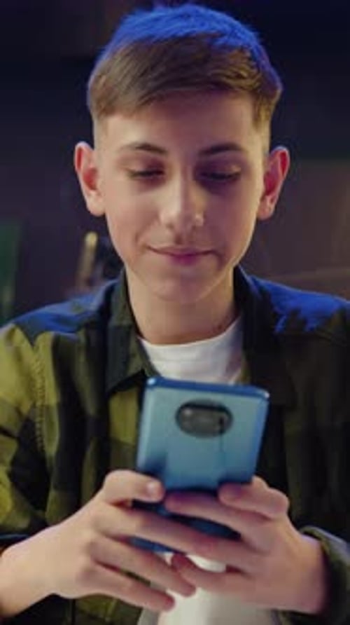Teen Boy Using Mobile Phone Indoors at Home