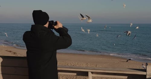 Man Tourist Looking Through Binocular Standing Against Sea Background