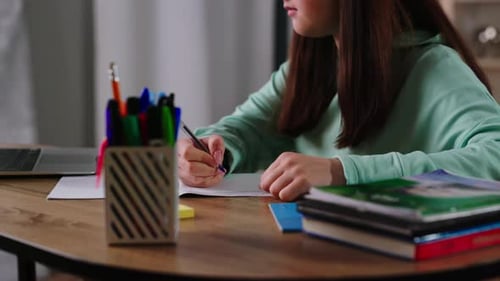 Teenage Girl Studying and Writing in Notebook