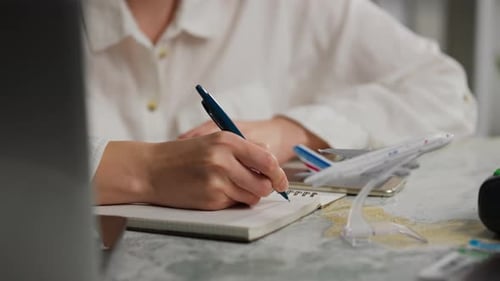 Person Planning a Trip, Writing in Notebook