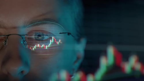 Trader Wearing Glasses is Working on Laptop Computer Screen with Stock Market Charts and Bitcoin BTC