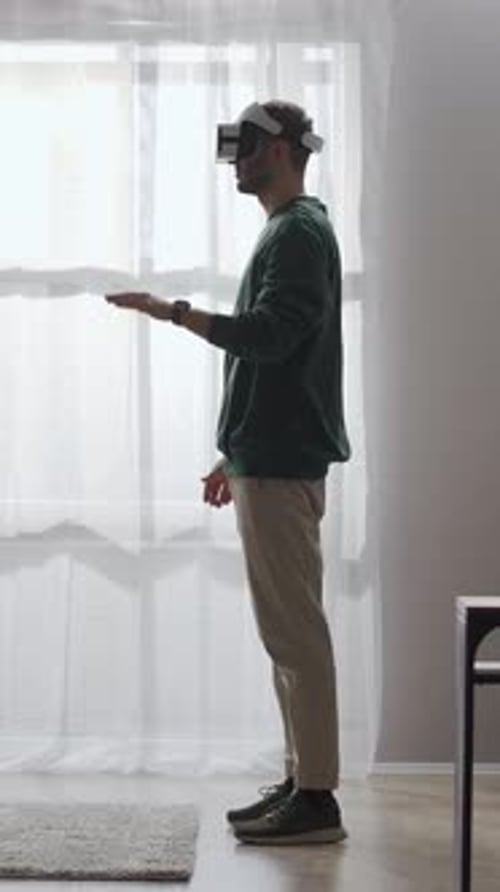 Side View of Young Man Exploring Immersive Virtual Reality Interface in Bright Minimalist Living