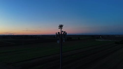 Telecommunication cell tower silhouette against a vibrant sunset sky