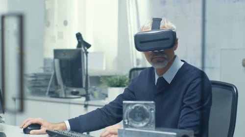 Virtual-Reality-Ingenieur arbeitet mit aufgesetzter VR-Brille und programmiert gleichzeitig auf seinem Handy