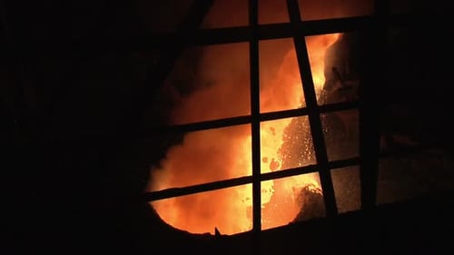 Molten metal pouring and swirling in dark factory