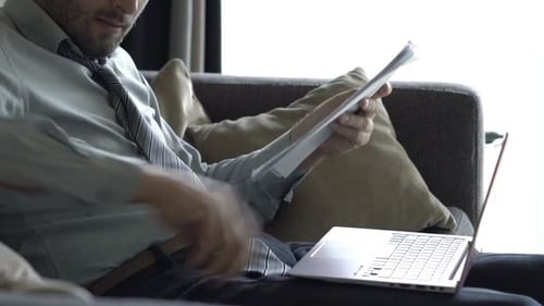 Man Reviews Documents While Working on Laptop