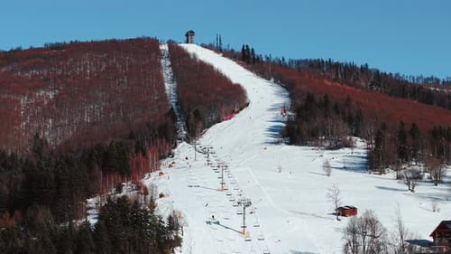Sunny Winter Aerial of Ski Slope with Skiers in Mountain Landscape