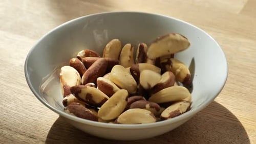 Brazil nuts in a white ceramic cup on a wooden table.Healthy fats