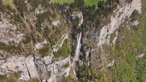 A dramatic waterfall cascading through rugged cliffs in a lush green valley, shot during the day, ae