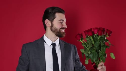 St. Valentine's Day. Handsome man with bouquet of roses on red background