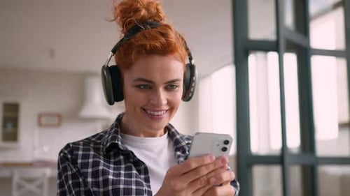 Smiling Woman with Headphones Using Mobile Phone Indoors